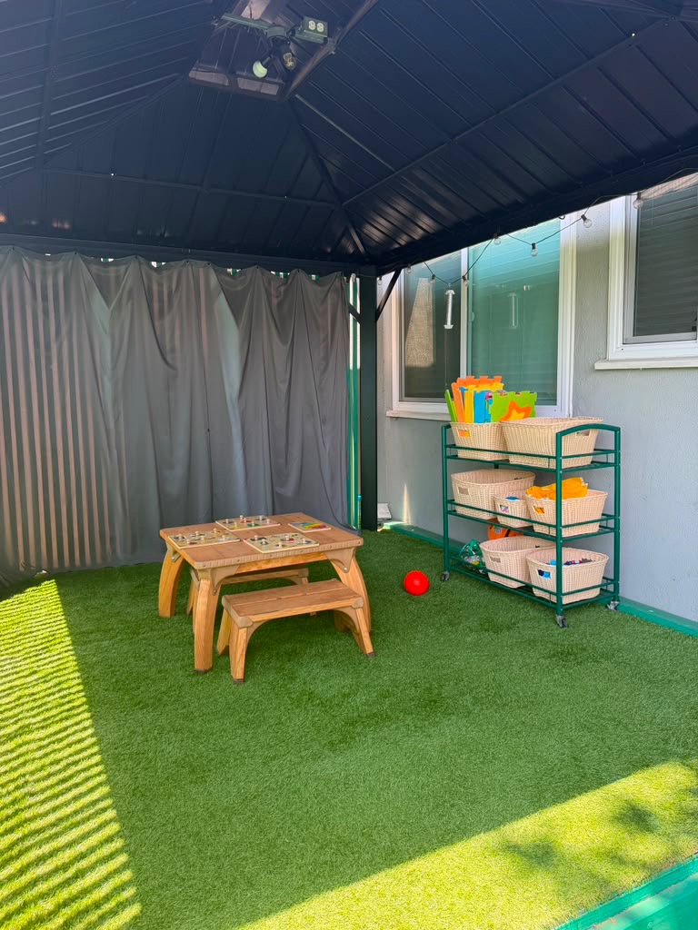 Child sized tables and activity shelves in the covered learning area